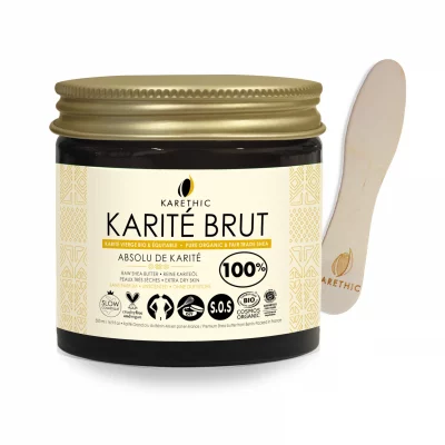 Beurre de karité brut, bio et issu du commerce équitable, dans un pot en verre avec une spatule en bois